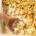A wooden spoon scooping up chicken and stuffing casserole.