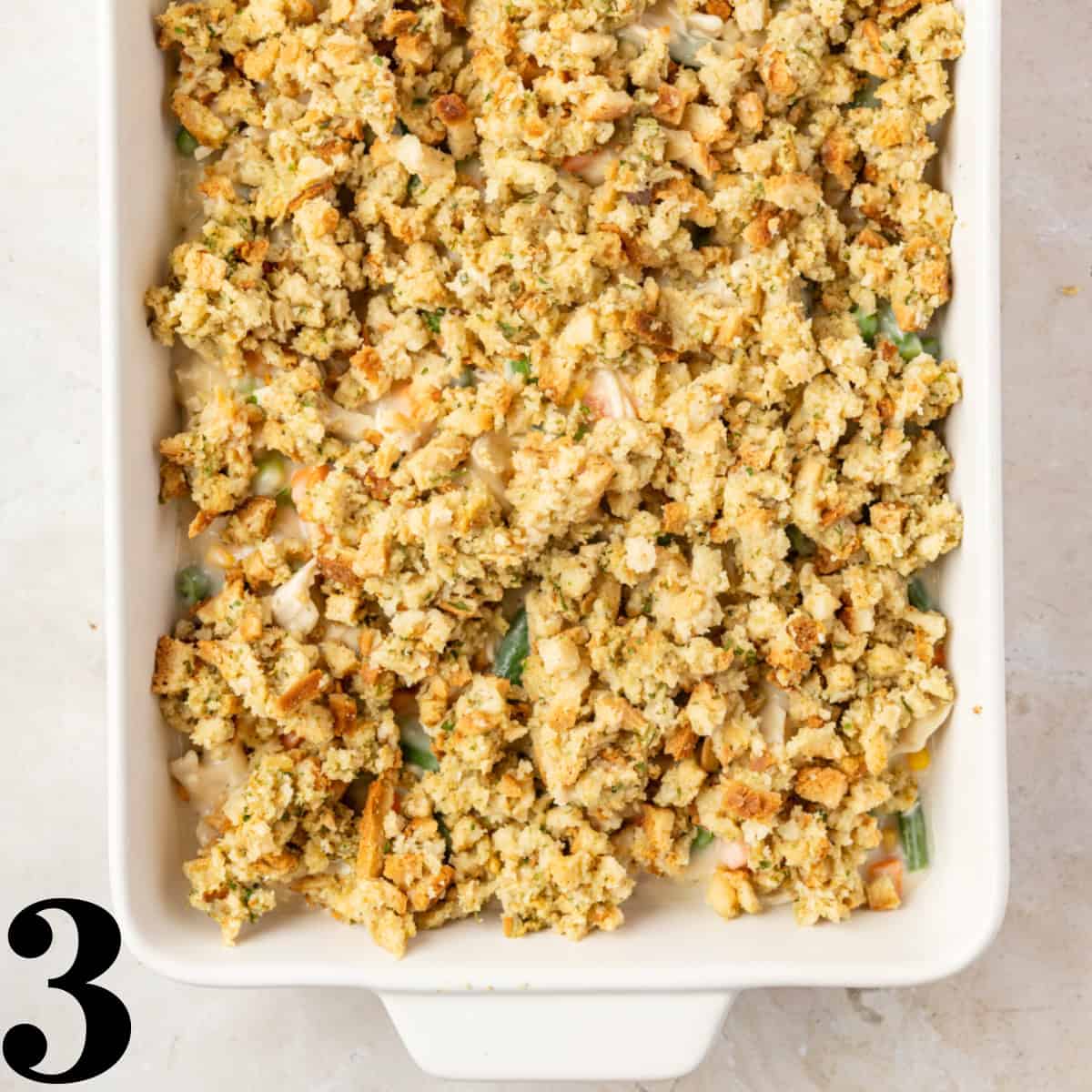 A white baking dish with chicken casserole topped with stuffing inside.