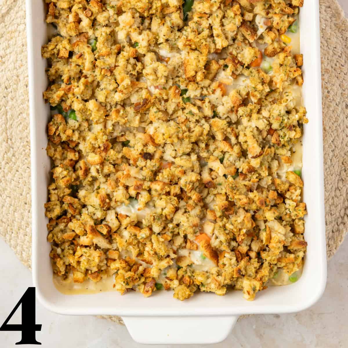 A white baking dish with chicken casserole topped with stuffing inside.