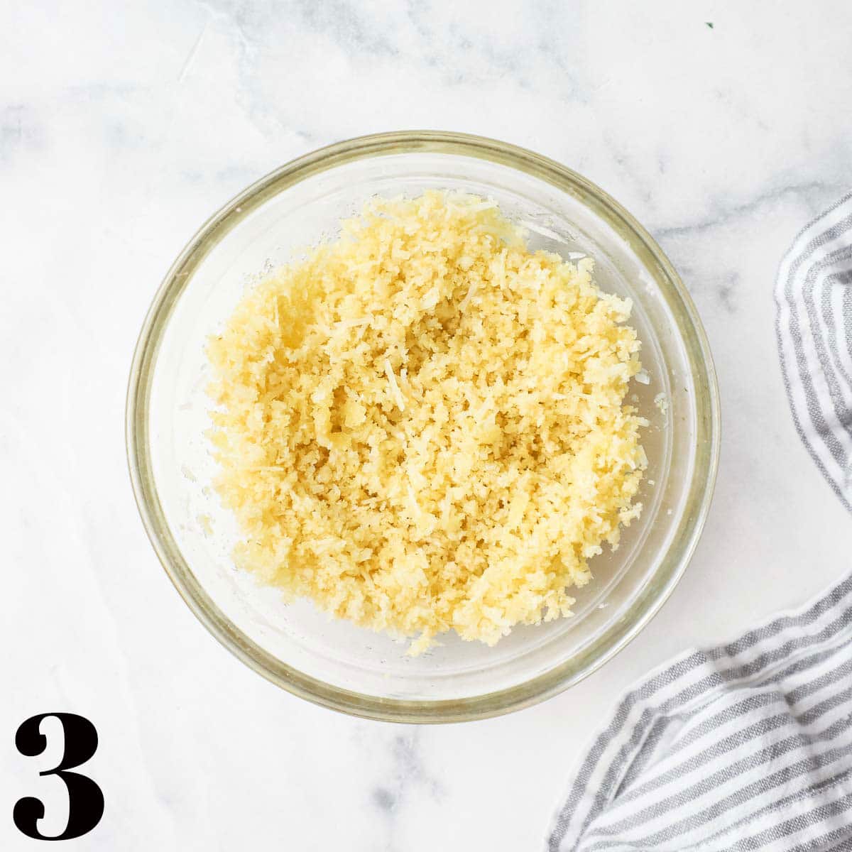 A glass bowl of parmesan cheese and bread crumbs.