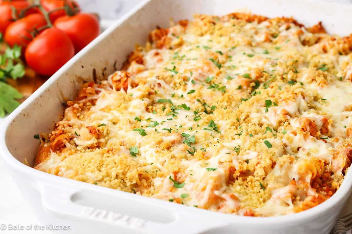 A white baking dish full of pasta and sauce topped with cheese.
