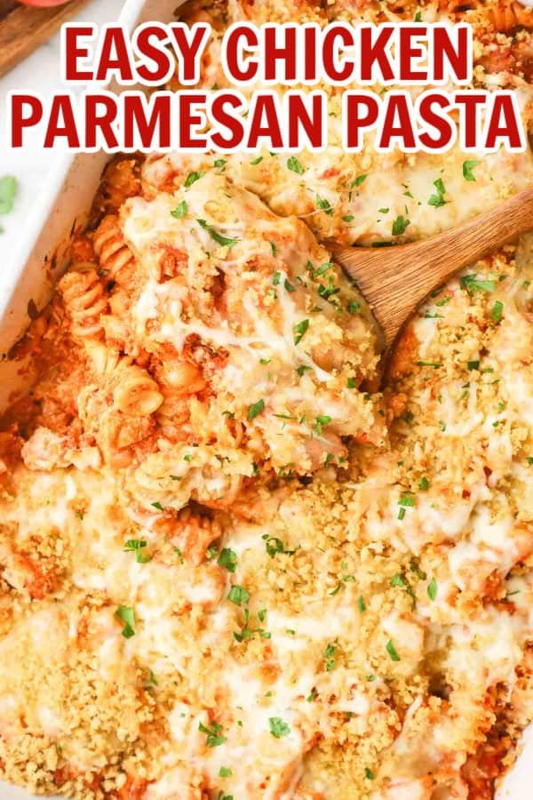 A baking dish full of chicken parmesan pasta with a wooden spoon dipping some out.